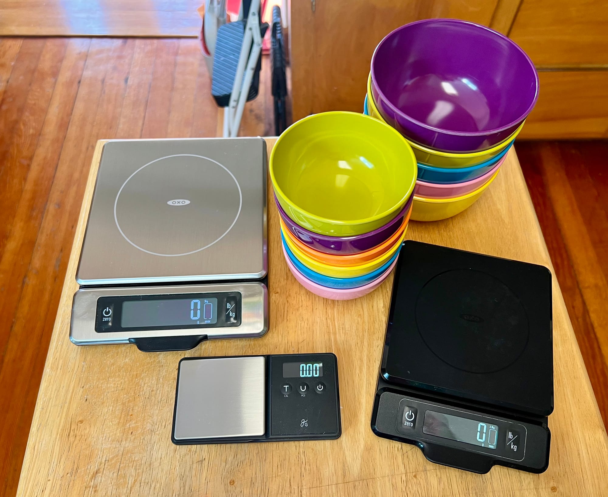 Three sizes of kitchen scale, and two stacks of small plastic bowls.