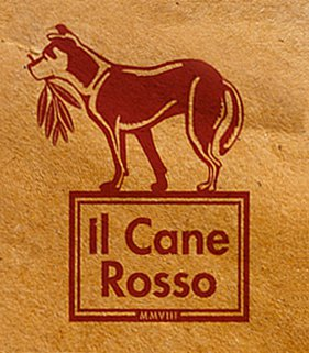 The logo for Il Cane Rosso, with a red dog holding a branch of laurel leaves in its mouth.