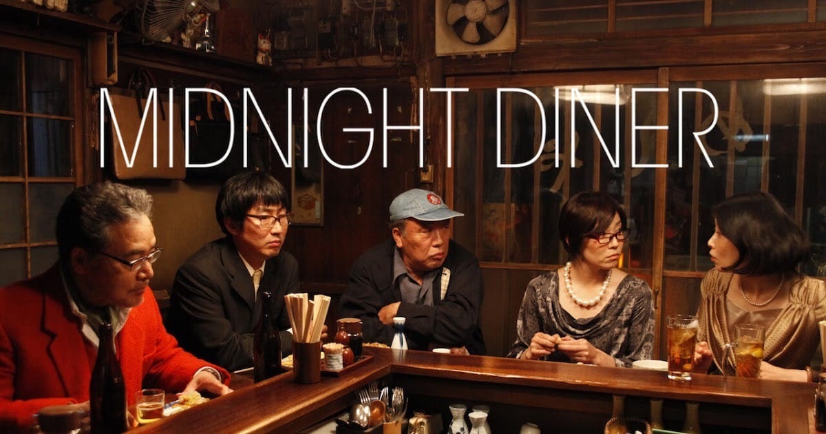 Five patrons sit at a counter in a small Japanese restaurant.