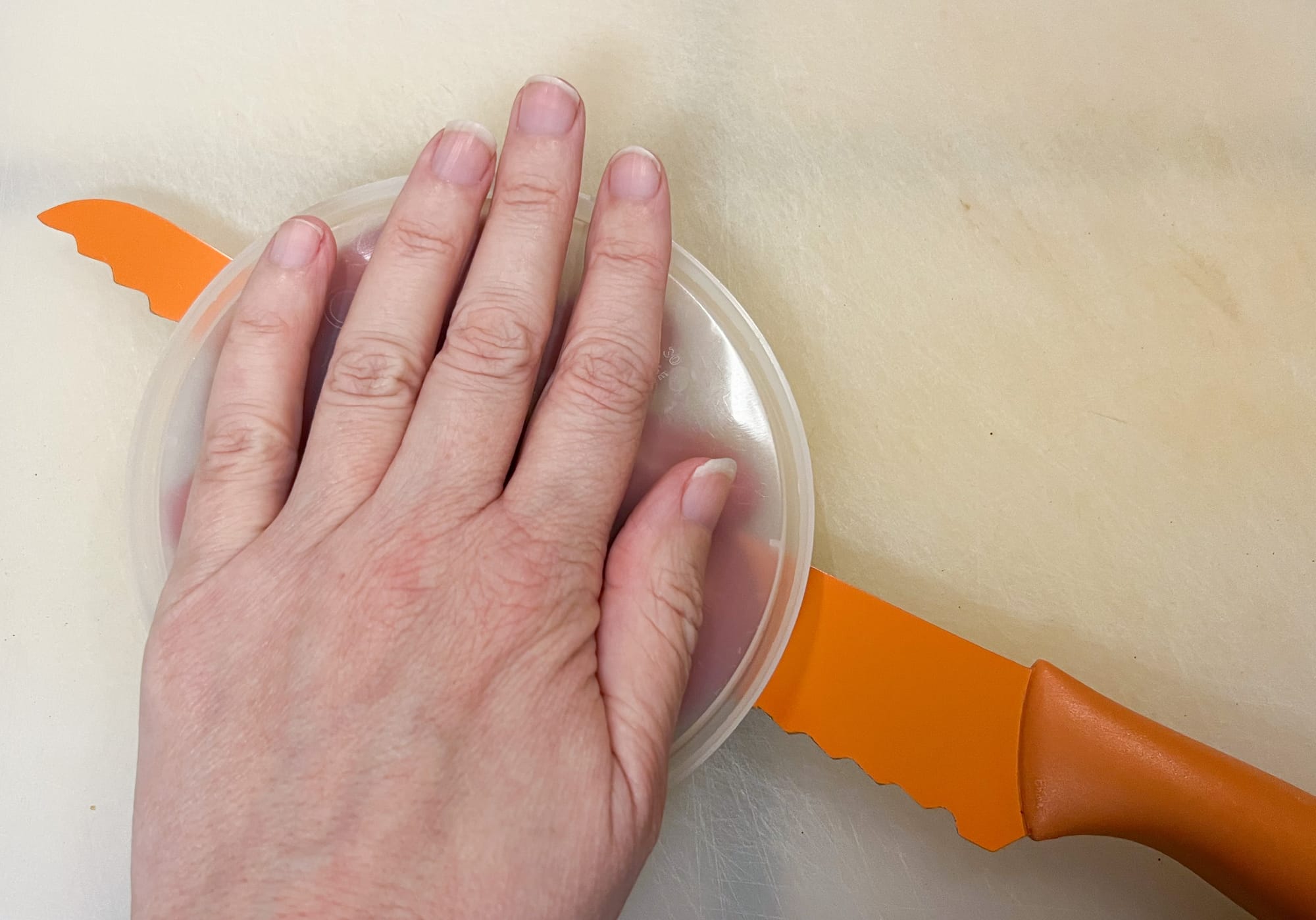 My left hand holds down the top lid, while the bread knife is cutting in between the two lids.