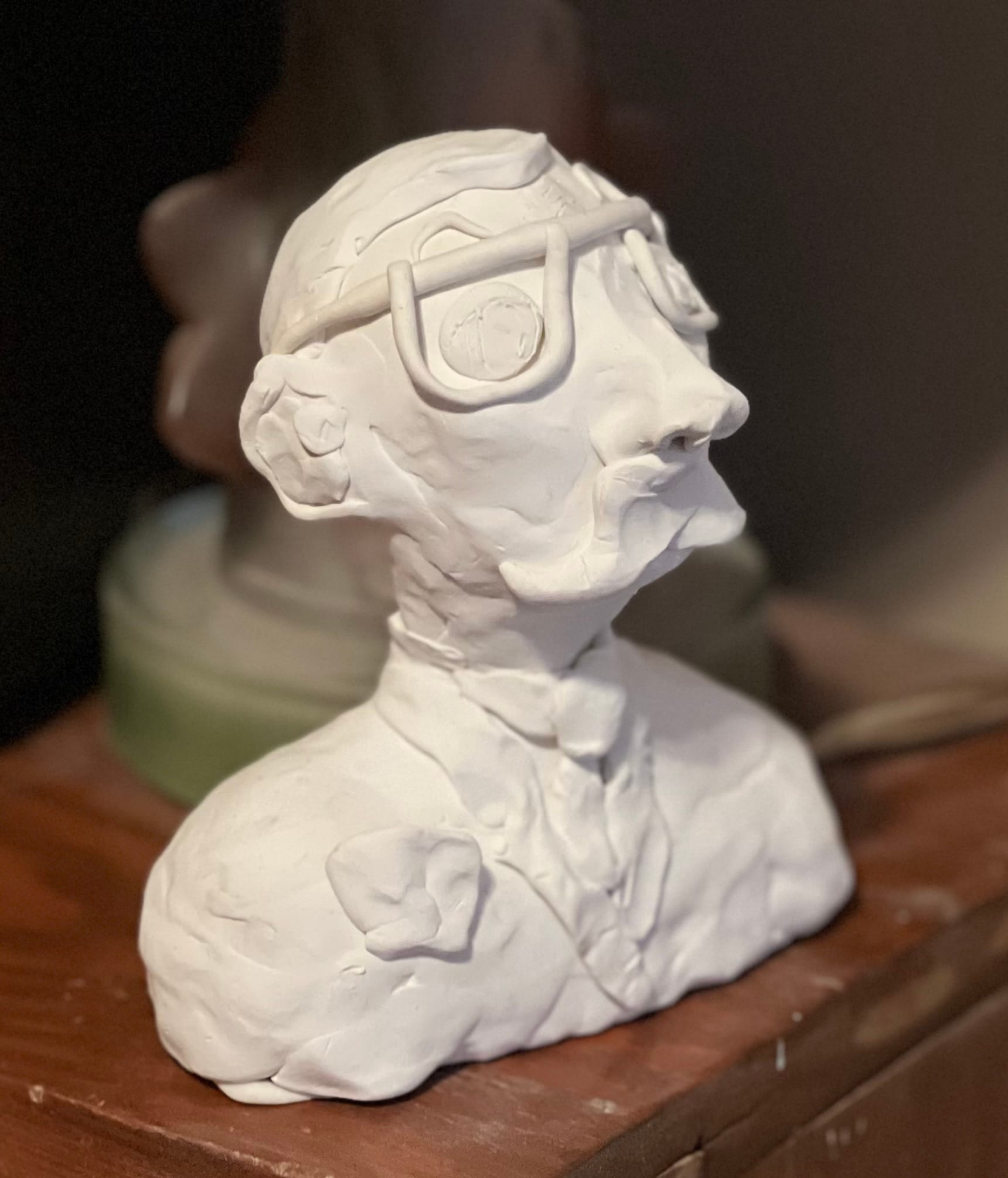 A small, white clay bust of Vince Guaraldi. He has glasses and a handlebar mustache.