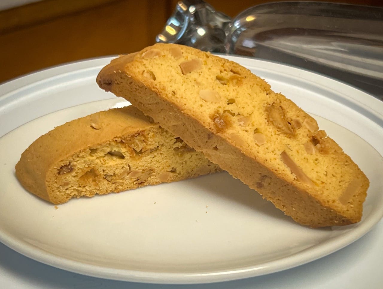 Two of the final baked cookies are on a small plate. They are golden brown.