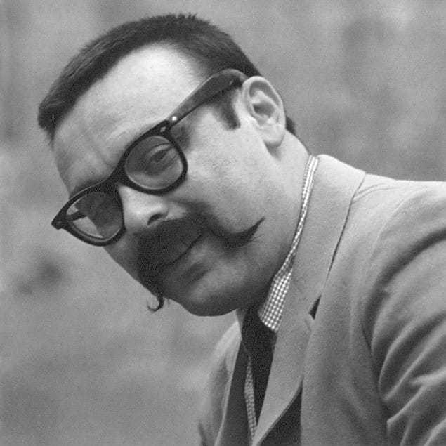 A close-up photo of Vince Guaraldi, with handlebar mustache and glasses. He's smiling.