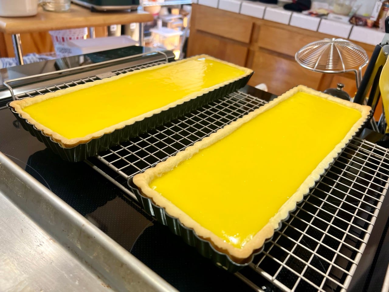 Two full rectangular lemon tarts are on a cooling rack.