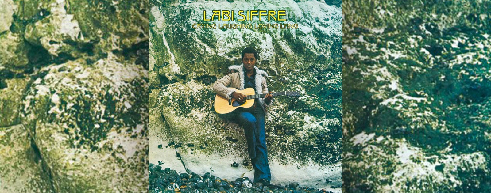 Album cover art, showing Labi Siffre holding an acoustic guitar, leaning against a moss-covered natural rock wall.