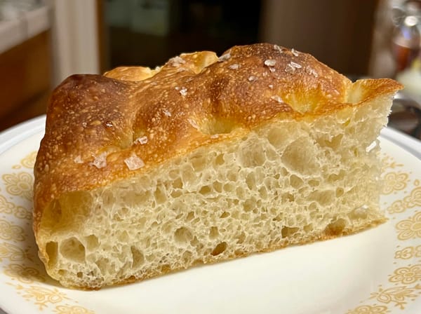 A slice of golden brown focaccia, topped with big flakes of salt.